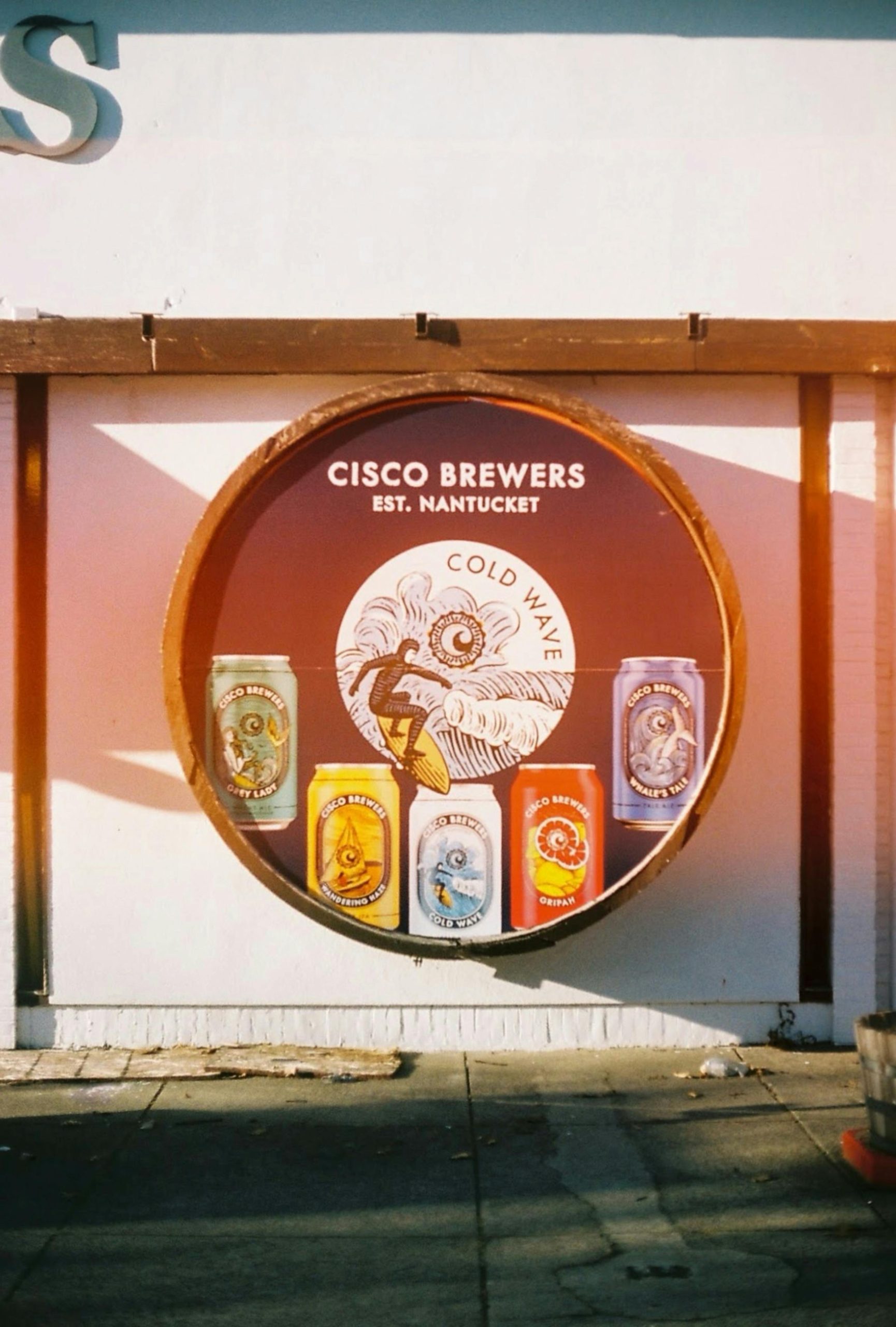 Colorful beer cans from Cisco Brewers on display in a vintage advertisement setting.